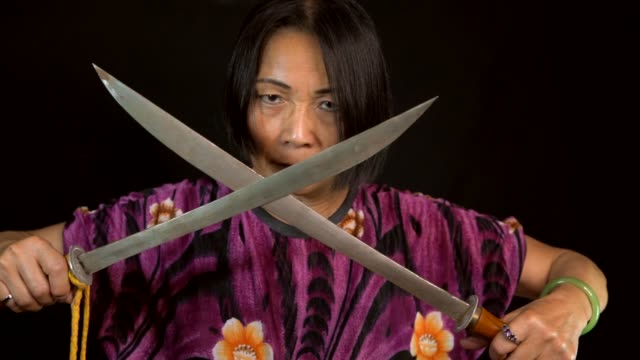 Slow-Motion-alte-einschüchternd-Asiatin-kreuzt-Schwerter-mit-schwarzem-Hintergrund
