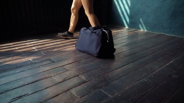 Closeup-young-fit-woman-legs-with-blue-bag-entering-fitness-club-and-preparing-for-boxing-training