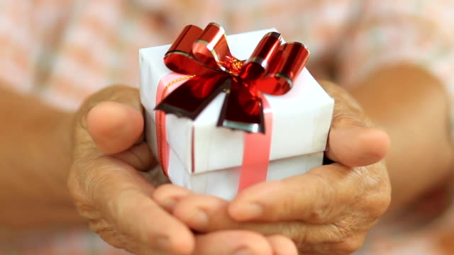 Senior-woman-holding-white-gift-insurance-and-healthy-care-concept.