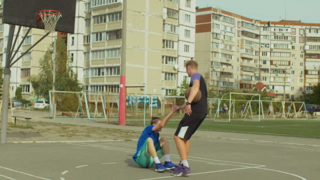 Jugadores-de-Streetball-ayudando-a-oponente-caído-a-levantarse