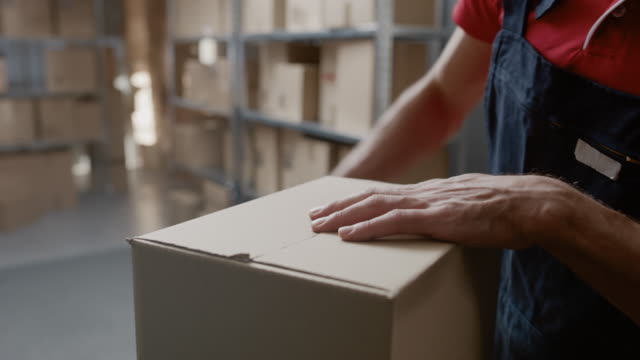 Warehouse-Worker-Kontrollen-und-Abdichtung-Karton-bereit-für-den-Versand.