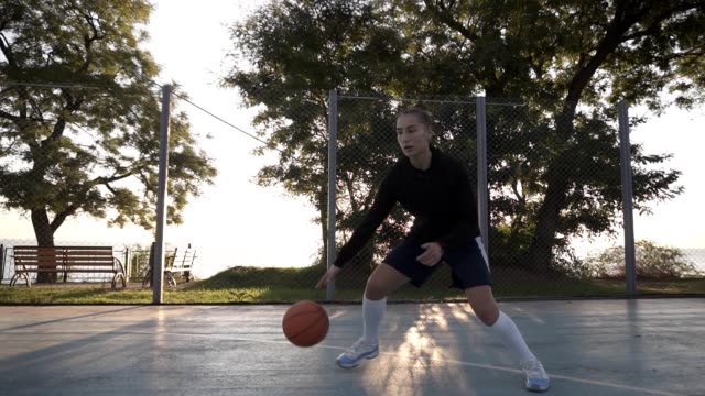 Footage-of-a-young-girl-basketball-player-training-and-exercising-outdoors-on-the-local-court.-Dribbling-with-the-ball,-bouncing-and-make-a-shot.-Slow-motion