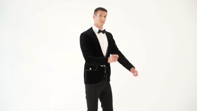 fun-man-in-a-black-suit-with-a-bow-tie-is-showing-dance-of-dancer-on-the-white-background