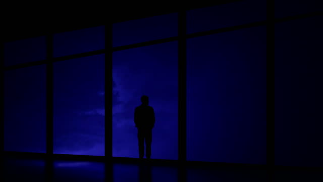 The-man-standing-near-window-on-the-night-thunderstorm-with-lightning-background