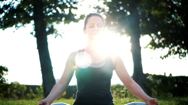 Schöne-schlanke-Frau-im-Lotussitz-praktizieren-Yoga-im-park