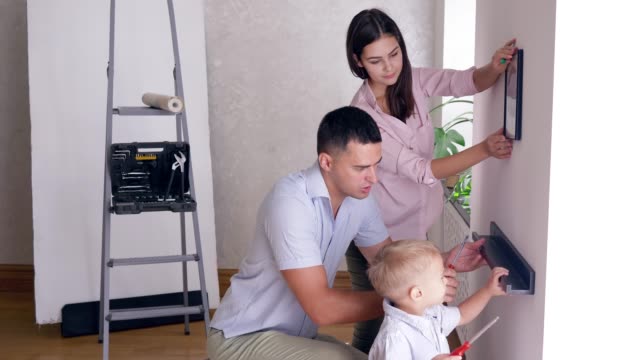 father-teaches-little-son-to-bolt-shelf-to-wall-with-screwdriver-while-repairing-apartment