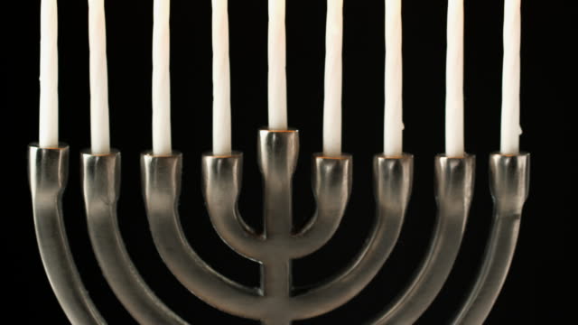 Inclinación-plano-de-candelabro-menorah-judía-con-velas-encendidas-sobre-fondo-negro