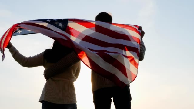 Hintere-Ansicht-patriotischen-Familie-mit-eine-große-Fahne-von-Amerika