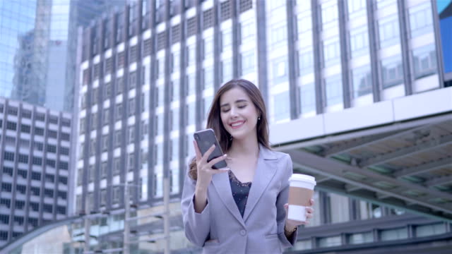 Joven-empresaria-caucásica-utilizando-teléfonos-inteligentes-están-caminando-y-toma-café-en-el-centro-de-Tailandia.--comunicación,-concepto-de-tecnología-de-la-vida-diaria.-CÁMARA-LENTA
