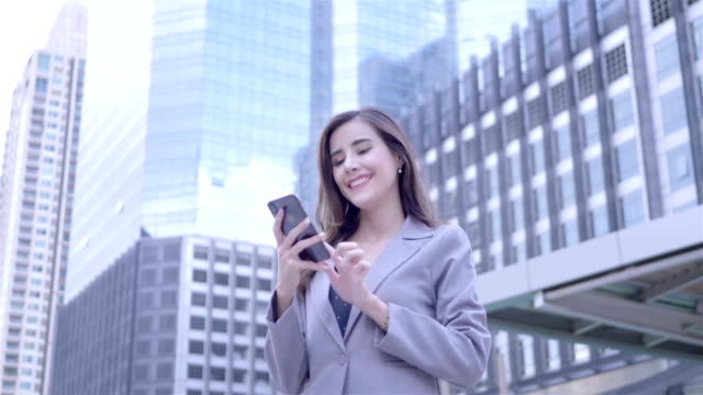 Kaukasische-junge-Geschäftsfrau-mittels-Smartphone-sind-Fuß-im-Stadtzentrum-von-Thailand.--Kommunikation,-Alltag-Technologiekonzept.-SLOW-MOTION