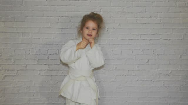 Mädchen,-Kind-in-einem-Kimono-auf-Karatetraining-klappt-Schläge-und-Gruß