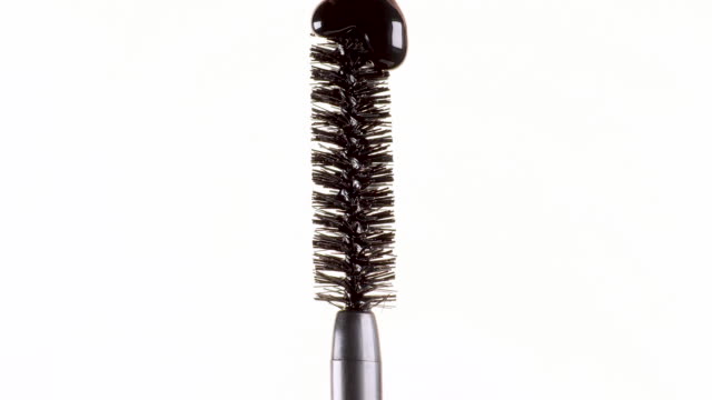 drops-of-black-mascara-fall-on-the-brush-on-a-white-background