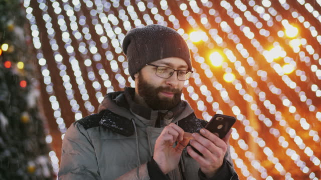 Hombre-barbudo-usar-aplicación-para-smartphone,-luces-de-Navidad