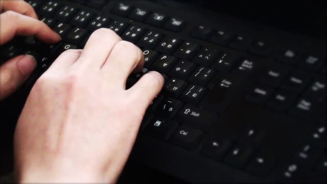 Man-tippt-auf-keyboard.using-computer-in-the-dark-room.