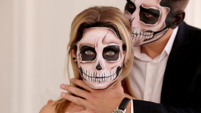 Un-hombre-con-maquillaje-de-Halloween-está-sosteniendo-A-su-novia-en-el-cuello.