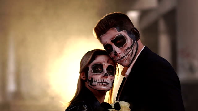 Ehepaar-mit-dunklem-Schädel-Make-up-auf-dem-Hintergrund-von-brennendem-Feuer-und-Rauch.