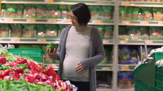 Mujer-asiática-embarazada-comprando-verduras-en-el-mercado
