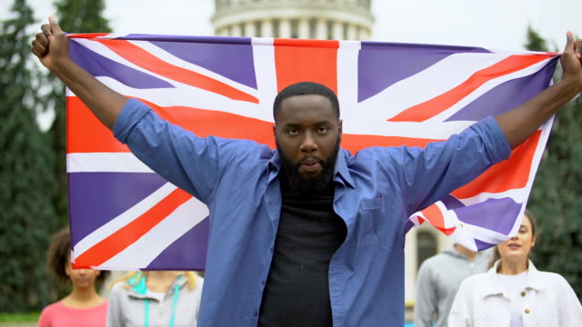 Wütender-schwarzer-Mann,-der-Großbritannien-Flagge-hisst,-Brexit-Protest,-Migrationskrise