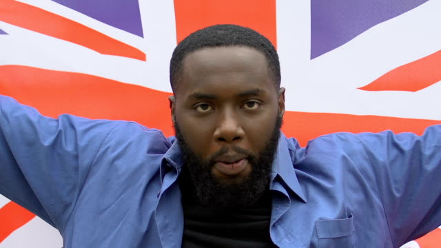 Angry-black-man-raising-Great-Britain-flag,-brexit-protest,-migration-crisis