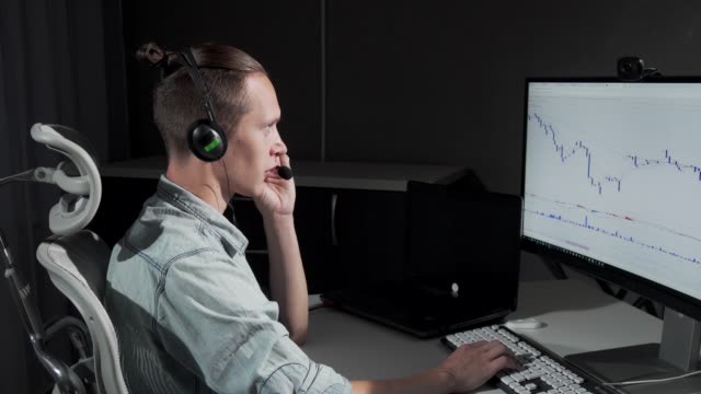 Junger-Mann-mit-Headset-mit-Mikrofon-arbeitet-online-spät-in-der-Nacht