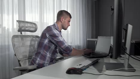 Guapo-trabajador-de-oficina-de-TI-usando-dos-computadoras-que-trabajan-en-un-proyecto