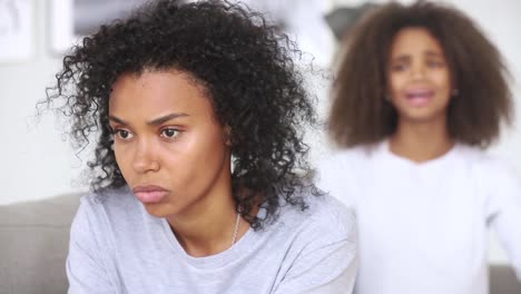 Irritated-angry-african-mother-and-apologizing-daughter-on-background