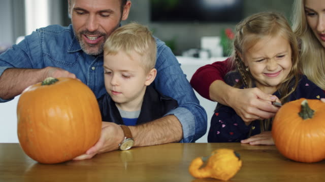 Parents-helping-children-in-carving-pumpkins