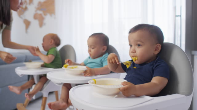 Three-Asian-Toddler-Siblings-in-High-Chairs-Eating-Puree