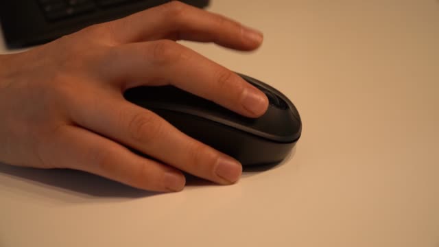 Young-female-hand-using-black-computer-mouse-on-white-table