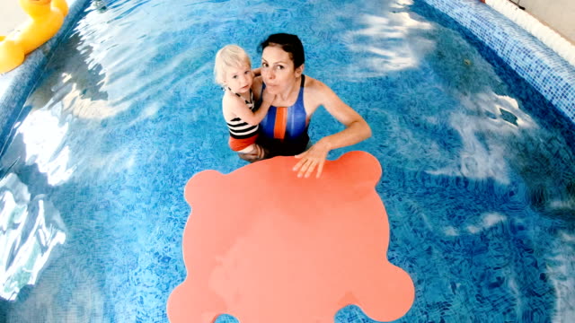Piscina.-Mamá-le-enseña-a-un-niño-pequeño-a-nadar-en-la-piscina.