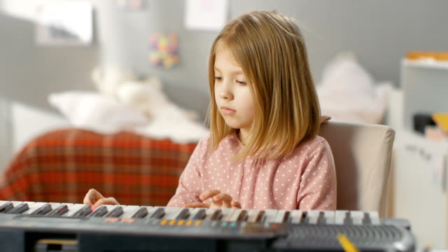 Talentoso-joven-aprende-a-tocar-el-sintetizador.-Ella-está-en-su-acogedora-habitación.