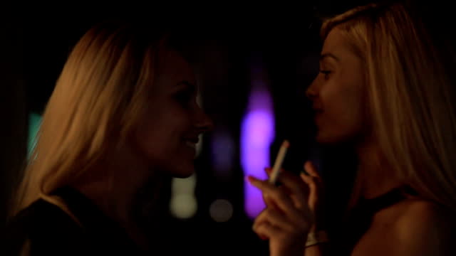 Excited-young-women-wasting-life-in-nightclubs,-dancing-and-smoking-cigarettes