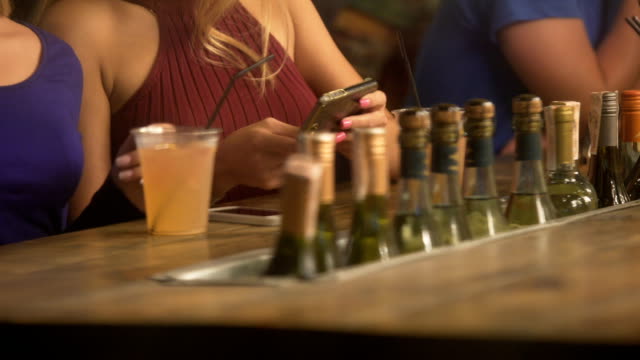 Glamorous-blonde-ladies-watching-video-on-smartphone,-having-fun-at-party-in-bar