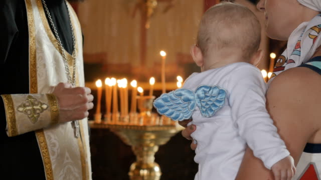 Mutter-hält-einen-kleiner-Junge-in-Armen-und-hört-einen-Priester-in-der-Kirche
