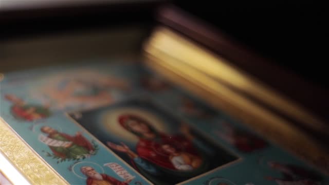 Icon-image-of-Virgin-Mary-in-St-Nicholas-Orthodox-Cathedral-in-Nice-France-macro-close-up-light-moving.-Framed-painting-of-Mother-of-God-in-Orans-position-with-Child-Jesus-attended-by-saints