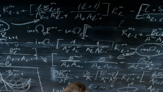 High-Angle-Shot-of-a-Brilliant-Young-Student-Writing-Big-Sophisticated-Mathematical-Formula/-Equation-on-the-Blackboard.