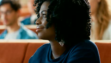 Retrato-de-una-muchacha-negra-joven-inteligente-y-hermosa-escuchar-una-conferencia-en-un-aula-llena-de-estudiantes-Multi-étnica.-Jóvenes-en-la-Universidad.