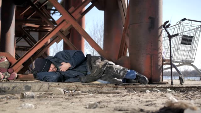 Cold-homeless-beggar-sleeping-under-bridge