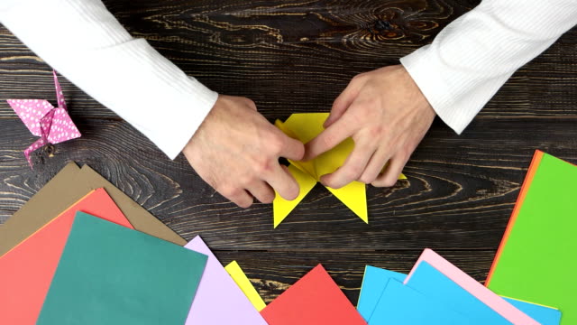 Man-folding-origami-figure,-top-view.