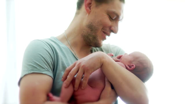 A-mature-father-cradle-his-month-old-baby-in-the-arms.-The-man-laughs-happily.-Father's-Day.-Children's-Day