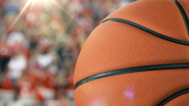 Bola-baloncesto-hermoso-primer-plano-a-cámara-lenta-en-el-fondo-del-estadio-con-la-llamarada-de-la-rotación.-Bucle-de-baloncesto-3d-animación-de-giro-bola.-4k-UHD-3840-x-2160.