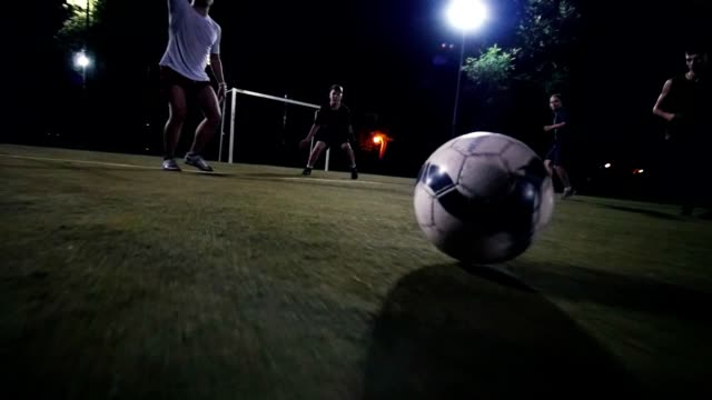 Fußballspieler-in-weißen-Turnschuhen-bewegt-sich-mit-dem-Ball-auf-das-Feld,-die-anderen-Spieler-Angriff,-Nacht-schießen