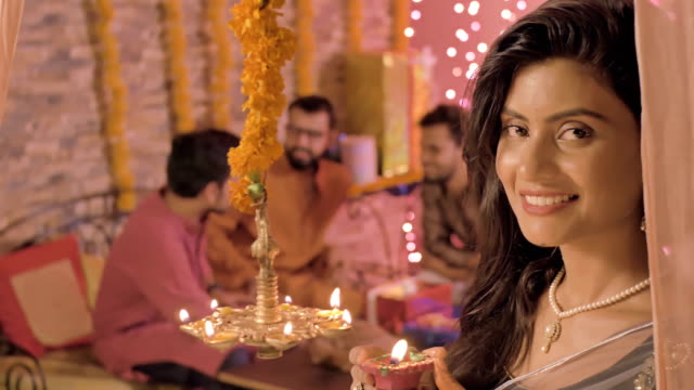 Eine-schöne-junge-Frau-in-einen-Sari-und-Ornamente-Lächeln-beim-Licht-einer-Öllampe