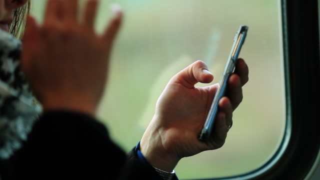 Nahaufnahme-der-Frau-die-Hände-halten-Smartphone-beim-Pendeln-mit-dem-Zug