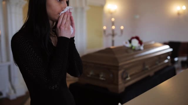 woman-with-wipe-and-coffin-at-funeral-in-church