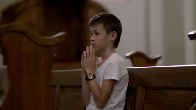 serious-boy-praying-in-the-Church-alone,-back-view