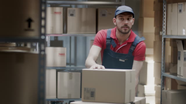 Warehouse-Worker-sammelt-Bestellung-durch-Einnahme-von-Kartons-und-Parzellen-im-Regal-und-setzen-sie-auf-ein-Trolley.