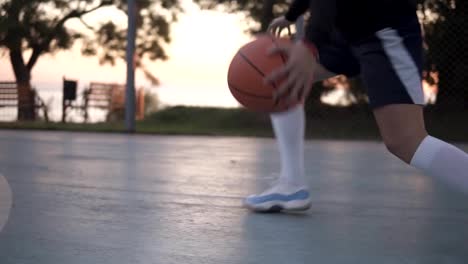 Close-up-footage-of-a-young-girl-basketball-player-training-and-exercising-outdoors-on-the-local-court.-Wearing-sportswear-and-white-socks,-sneakers