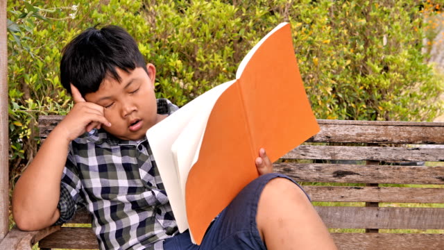 Süße-asiatische-Kinder-ist-gelangweilt-und-müde-mit-einem-Buch.-Bildungskonzept