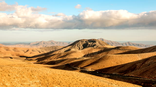 Timelapse-clouds-flying-over-dry-mountains-and-smooth-hills,-Fuerteventura,-Spain